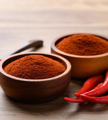 Red chili powder in bowl on wooden background, food seasoning